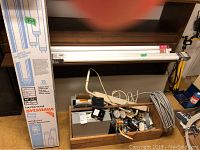 Photo of boxed Sylvania fluorescent bulbs, coiled cable, wooden caddy with manifold and electrical parts