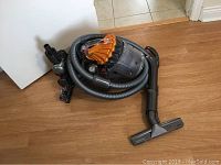 Vacuum and accessories arranged on wooden floor