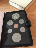 Photo showing open black presentation case with seven Canadian coins, including the 1976 double struck silver dollar commemorative coin featuring the Library of Parliament.