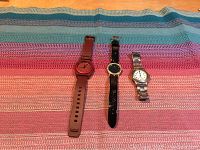 Three watches on a striped colored fabric background, showing full watches including straps.