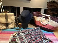 Lot showing all items together on colorful textile, including navy blue hat, canvas bag, large striped beach bag, and scarf.