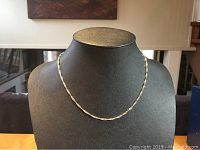 Front view of the twisted sterling silver chain necklace displayed on a black stand, showing the design and shine.