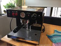 Front view showing portafilter, steam wand, control switches and pressure gauge