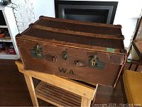 Side view of vintage suitcase on wooden stand, showing locking mechanisms and leather details.