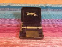 Open black Gillette case showing the vintage Gillette safety razor inside with purple velvet lining and gold branding on the case lid.