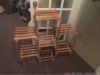 Full view of wooden multi-tier plant stand on carpeted floor showing three horizontal slatted shelves for plant placement.