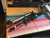 Bushnell telescope with tripod resting on a wooden surface, along with a visible carry bag in the background.