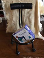 Adjustable black metal balance ball chair frame with padded backrest and wheels, with the boxed Gaiam Balance Ball Fitness Kit on the chair seat.