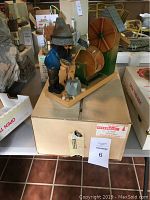 Front and left side view of the Steinbach music box showing the woodcutter figure, waterwheel, and sawmill detail on a box.