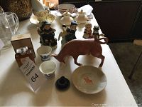 Photo showing vintage Chanel No. 46 perfume bottle along with small figurines, cups, and a bull figurine arranged on a table.