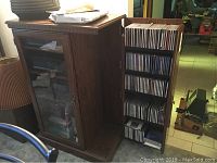 Wooden cabinet with glass door open on right showing CD rack filled with CDs