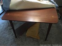 Full view of the mid century modern dining table showing the wooden surface, tapered legs, and brass inlay X detail on corners.