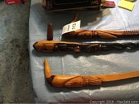 Three carved walking sticks laid on a surface, showing different carvings and wood tones.