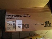 Top view of the boxed RCA dual-cassette dubbing deck, showing product description text about high-quality dubbing and auto-reverse features.