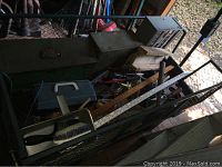 Photo showing the contents of the green 4-wheel garden wagon with various hand tools including brushes, rulers and metal boxes.