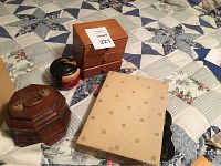 Four jewelry boxes displayed on a quilted bedcover, showing variety in materials and shapes