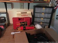 Photo of table with the jigsaw box, soldering kit box, flashlight, nuts and bolts organizer, and cooler visible.
