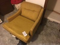 Photo showing the chair angled with mustard yellow fabric, wood frame base, and cushioned armrests.