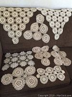 Photo showing 8 vintage crocheted doilies in various shapes arranged on a brown fabric surface, highlighting their intricate patterns and varying sizes.
