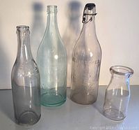 Four antique glass bottles from Worcester Ma, including Vandale pale green bottle, blue ribbon chocolate milk bottle, Bowlers Bros., and George Hewitt with metal stopper