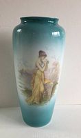 Front photo of turquoise gradient Rosenthal porcelain vase featuring hand painted classical portrait of woman in yellow dress by floral stone pedestal.