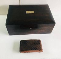 Top view of dark wooden vintage humidor box with small curved accessory piece in front.