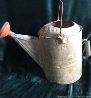 Front and side view of vintage galvanized metal watering can showing conical red-painted spout and side handle