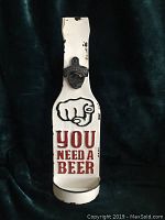 Full view of the enamelware metal bottle opener sign showing shape, text, and bottle opener.