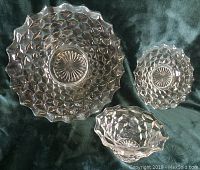Three clear pressed glass pieces with honeycomb pattern displayed on dark fabric for size and detail.