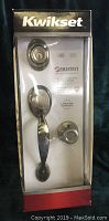 Front view of Kwikset Dakota door handle set in box, showing handle, lock cylinder, and knob with SmartKey branding and product details.