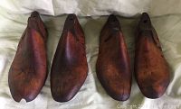 Top view of four wooden shoe forms showing the length and overall shape with visible marks and holes.
