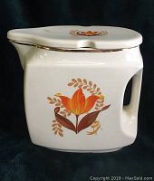 White square-shaped water pitcher with built-in handle, decorated with orange and brown tulip motif and gold trimming on rim and lid.