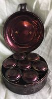 Open spice caddy with 7 smaller tins inside, viewed from above to show lid interior and tins