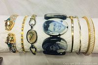 Seven costume bracelets arranged side-by-side for full lot view, highlighting design variety including animal motif, photo cameo, and plain bangles.