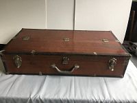 Closed view of the large rectangular case showing metal edges, wood panels, metal latches, and handle