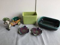 All five pieces shown including two small flower-shaped holders, green rectangular planter, dark green oval planter, and donkey cart planter