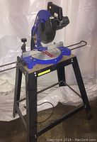 Side view of the Tradesmith miter saw mounted on a stand with black metal legs and wooden platform.