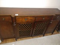 Front view of buffet server showing three upper drawers, two decorative lattice cabinet doors, and side compartments with wood doors