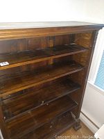 Full view of the antique wooden bookcase showing five shelves and overall structure.