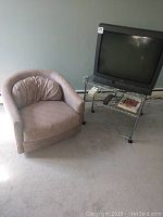 Photo showing chair, TV on metal rolling stand, remotes on shelf