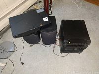 Sony audio system components with paired Sony speakers and Samsung Blu-ray player arranged on floor near stairway.
