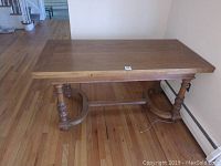 Full view of the vintage wooden dining table showing the tabletop and carved supporting legs.