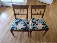 Pair of two matching antique wood chairs with floral upholstered seats and carved backs, showing overall seating and wood finish.