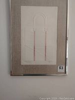 Framed wall art front view showing embossed bag design with red handles, beige matting and silver frame. Edition and signature visible on artwork corners.