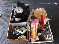 Photo showing the Krups espresso machine and two boxes filled with various household and kitchen items including decorative plates and cleaning brushes.