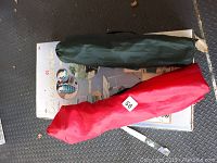 Two foldable chairs in green and red fabric carrying bags placed on top of the Out and About Roller Cart box.