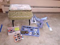 Wicker standing sewing box, sewing machine box, handheld steamer, shoelaces and sewing supplies on floor