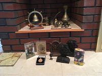 Wide front view of all items showing brass decor and Lincoln memorabilia arranged on floor and hearth.