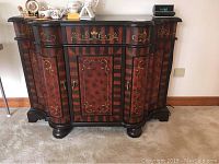 Front view of Quoizel butler cabinet showing intricate inlay designs, three doors, and rounded feet.