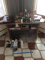 Wide view of wooden desk with various office supplies arranged, including calculators, portfolios, bookends, and document racks below the desk